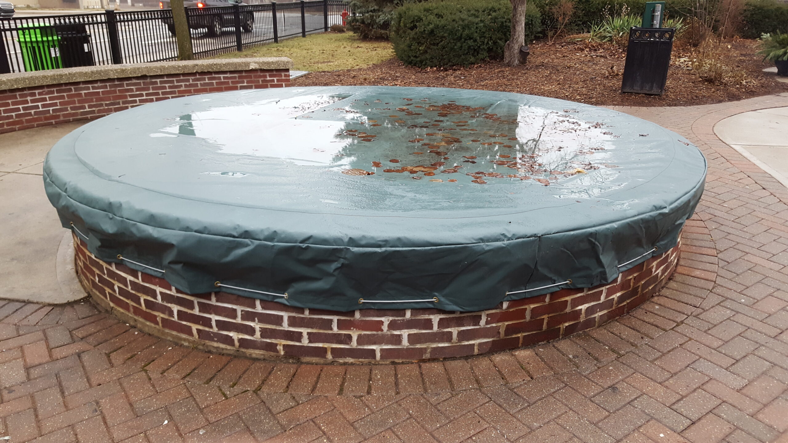 large outdoor fountain made of brick covered in a custom fountain cover with water on top